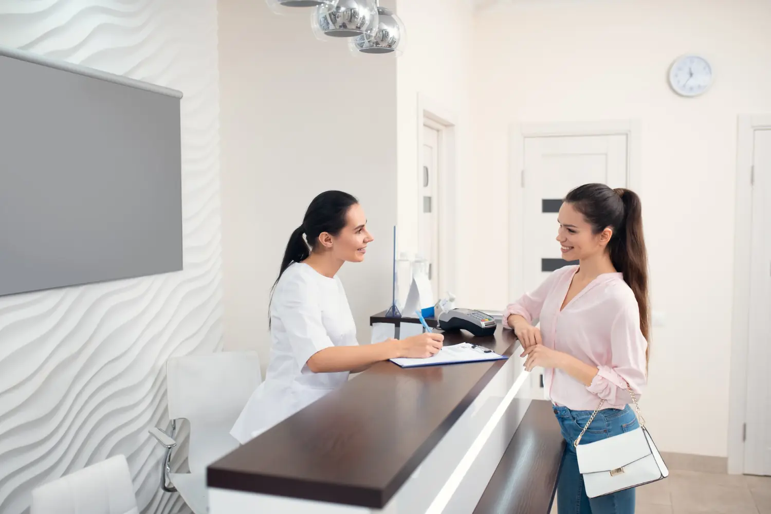 CNAE 8640-2/02 pode pedir equiparação hospitalar: Foto de uma recepcionista de clínica médica atendendo uma cliente