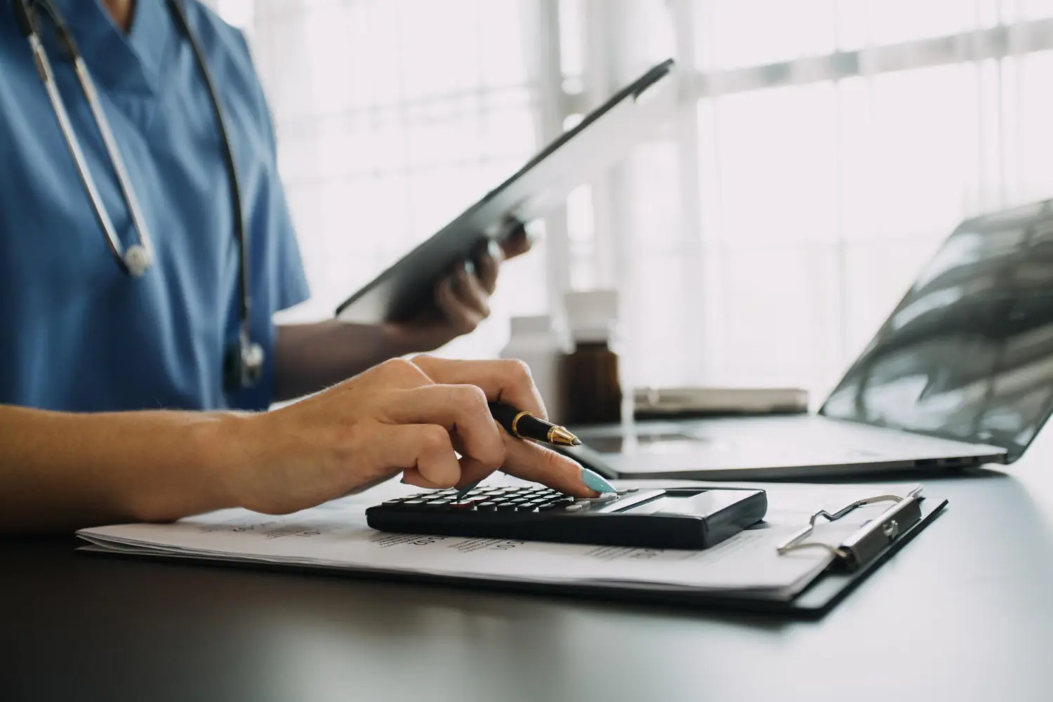 A diferença entre pró-labore, dividendos e salário para o médico-sócio: Foto de uma médica fazendo cálculos tributários