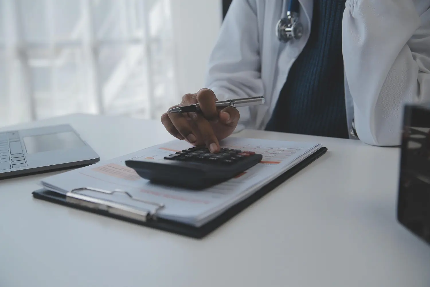 Como renegociar dívidas da clínica médica: Foto de um médico fazendo cálculos tributários