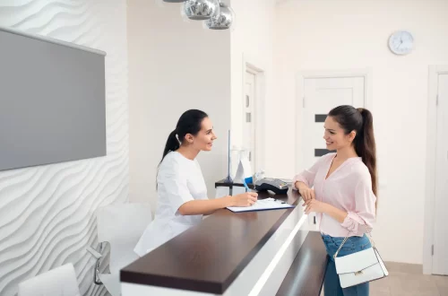CNAE 8640-2/02 pode pedir equiparação hospitalar: Foto de uma recepcionista de clínica médica atendendo uma cliente