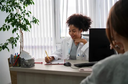 Equiparação hospitalar para clínicas médicas: Foto de uma médica atendendo paciente em sua clínica
