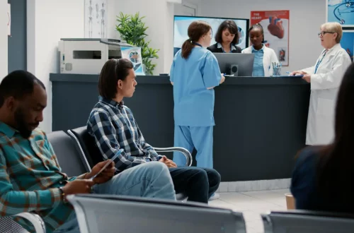 Lucro Presumido vs. Lucro Real para grandes clínicas: Foto de pacientes, médicos e enfermeiras na recepção de uma clínica