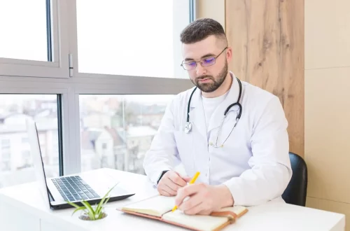 Conheça a reforma tributária para médicos: Foto de um médico em seu escritório fazendo cálculos tributários