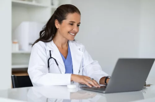 Melhores softwares de gestão financeira para clínicas médicas: Foto de uma médica acessando seu computador para fazer a gestão de sua clínica